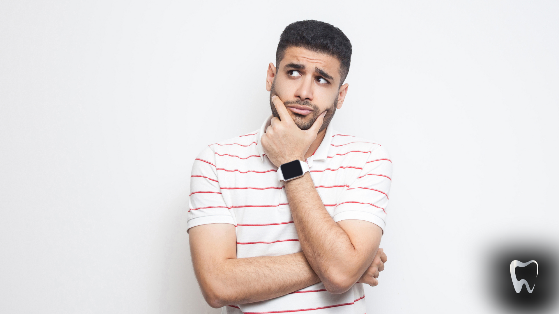 A man in a striped shirt is holding his hand to his chin and looking up.