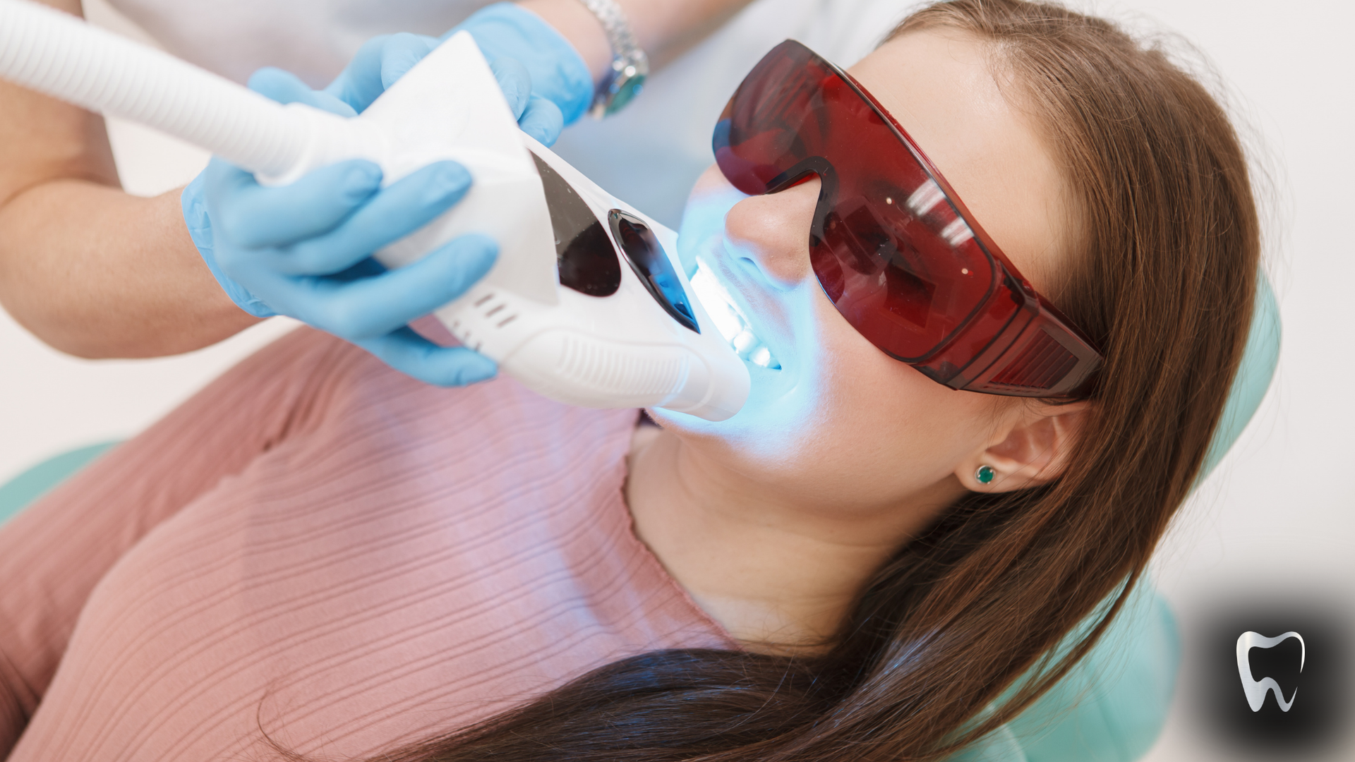 A woman is getting her teeth whitened in a dental office.