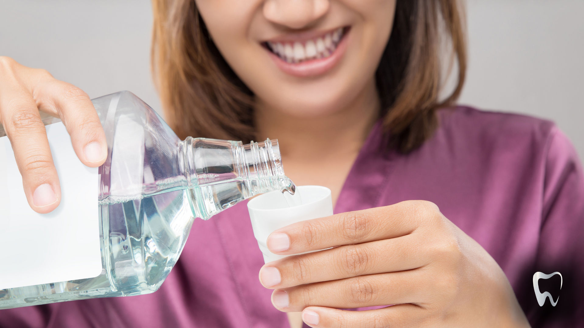 A woman is pouring mouthwash into a cup.