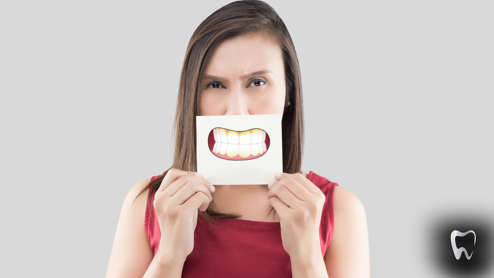 A woman is holding a piece of paper with a picture of teeth on it.