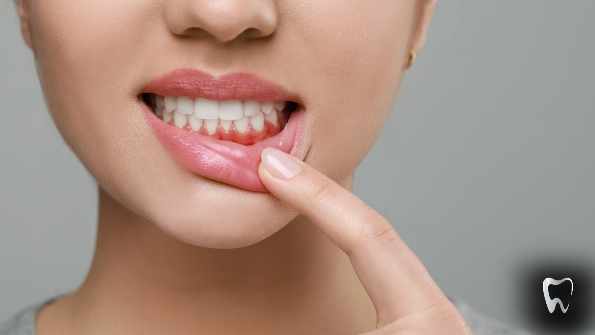 A woman is pointing at her teeth with her finger.