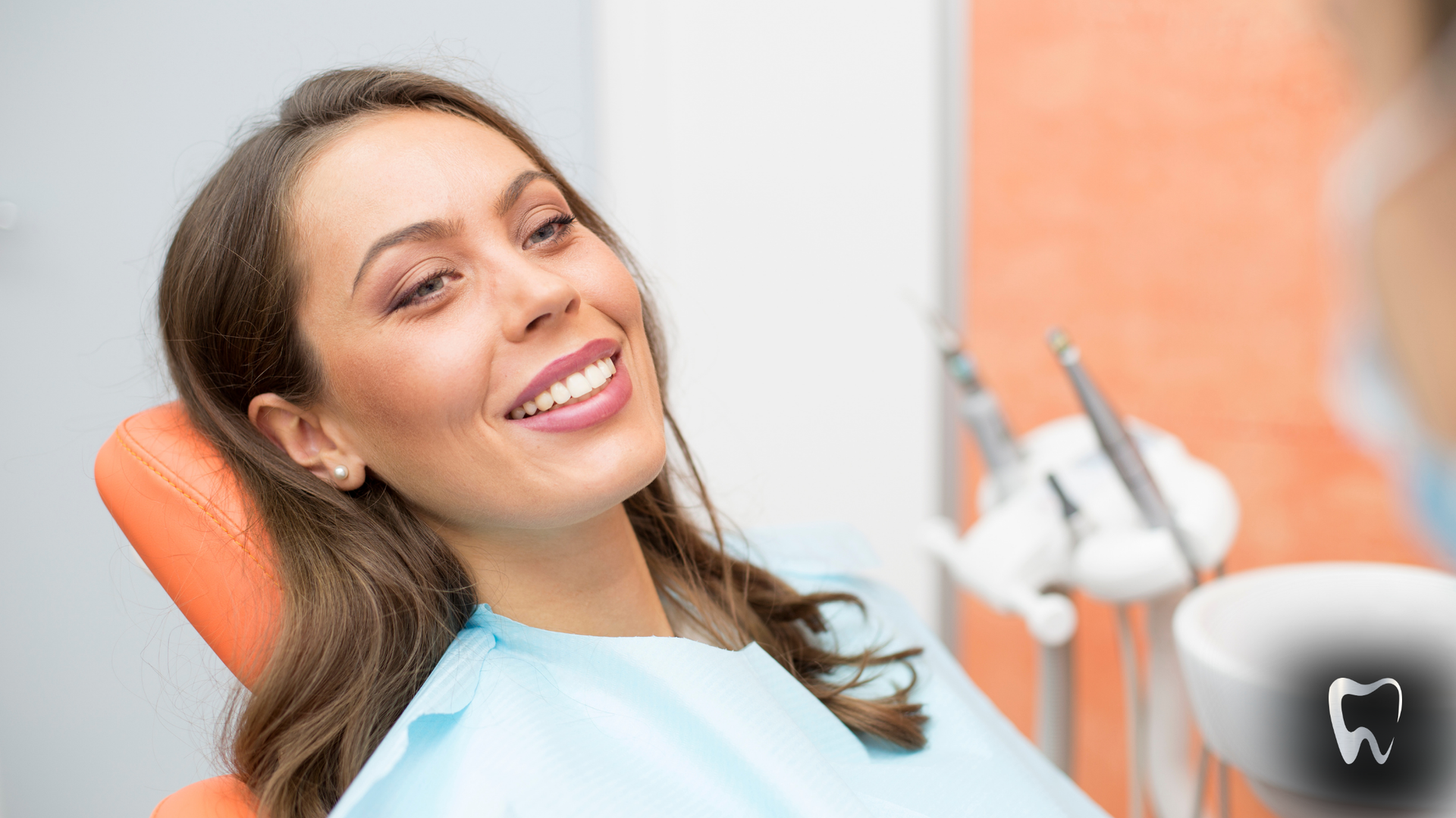 A woman is smiling while sitting in a dental chair.