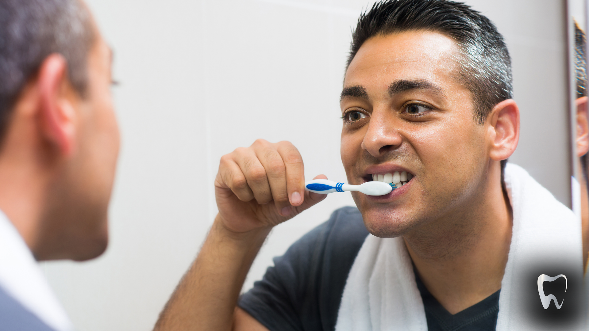 A man is brushing his teeth in front of a mirror.