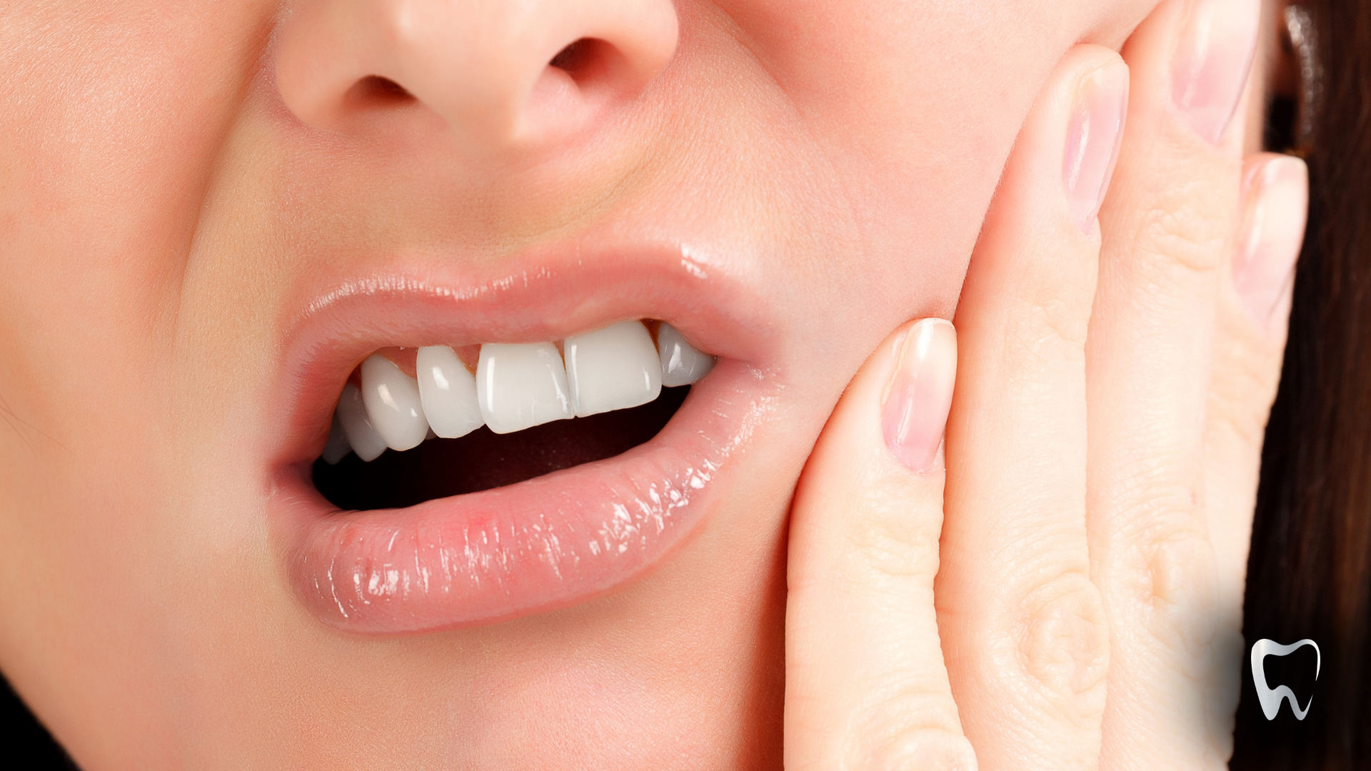 Woman with open mouth, hand on cheek, showing teeth, indicating pain.