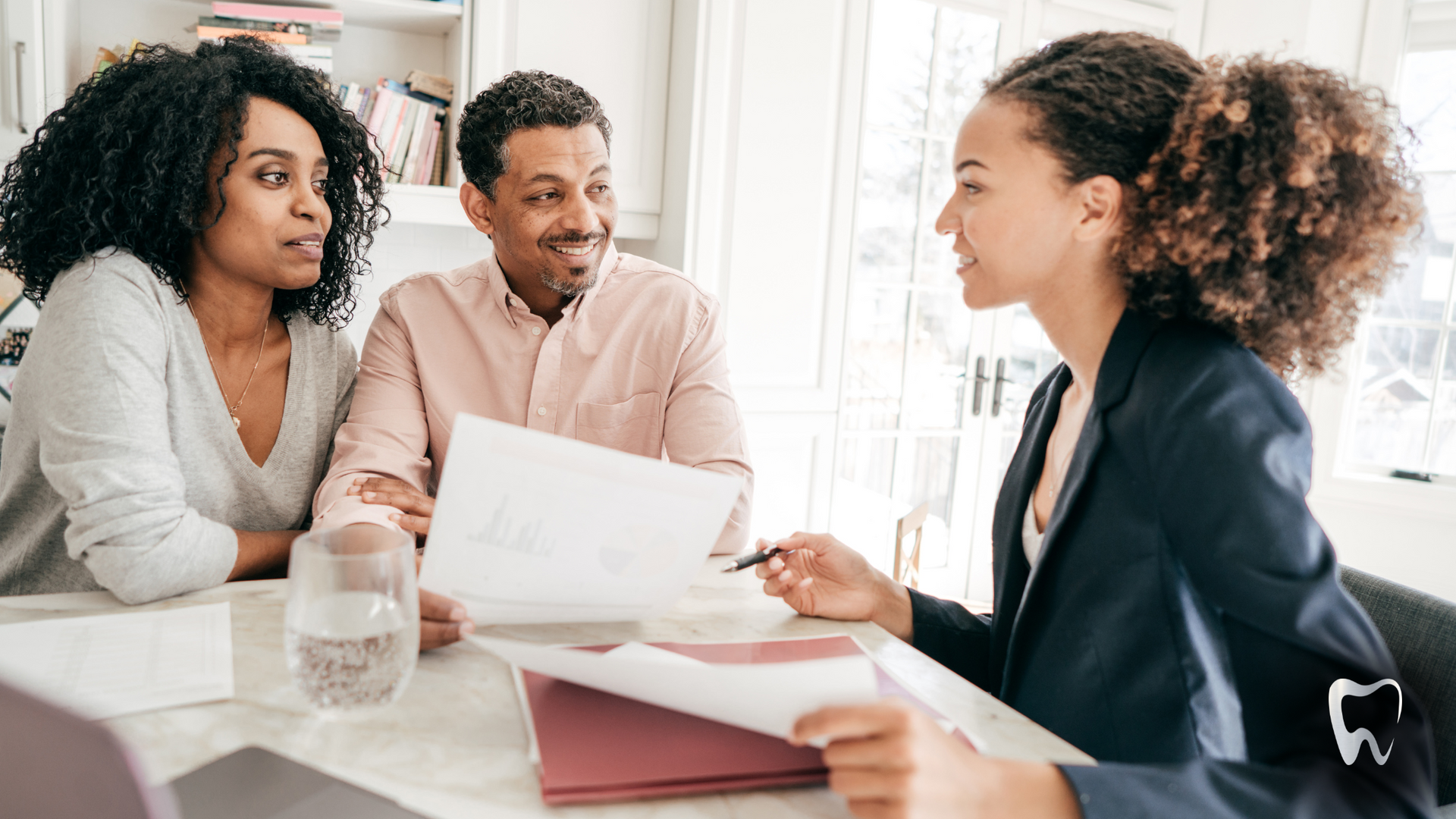 A woman is sitting at a table talking to a man and woman.