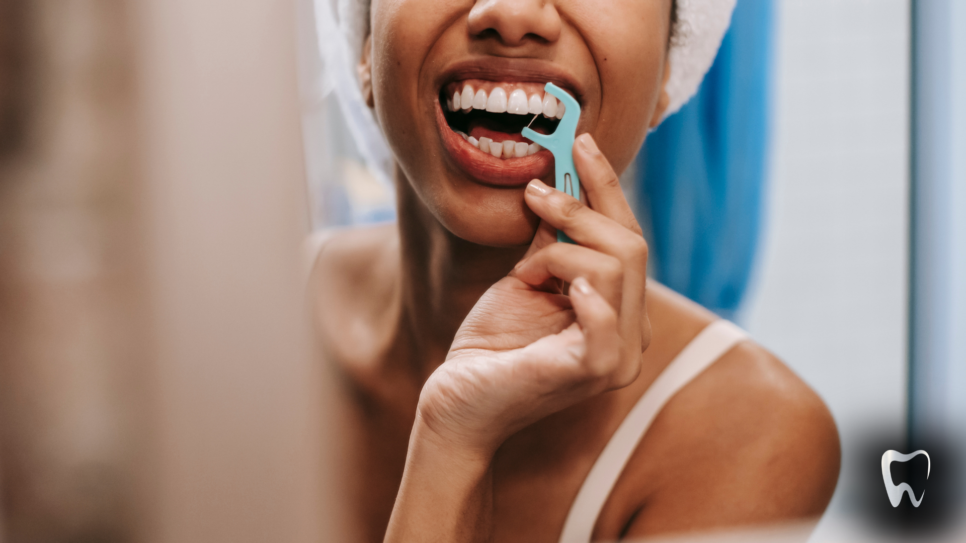 A woman is flossing her teeth in front of a mirror.