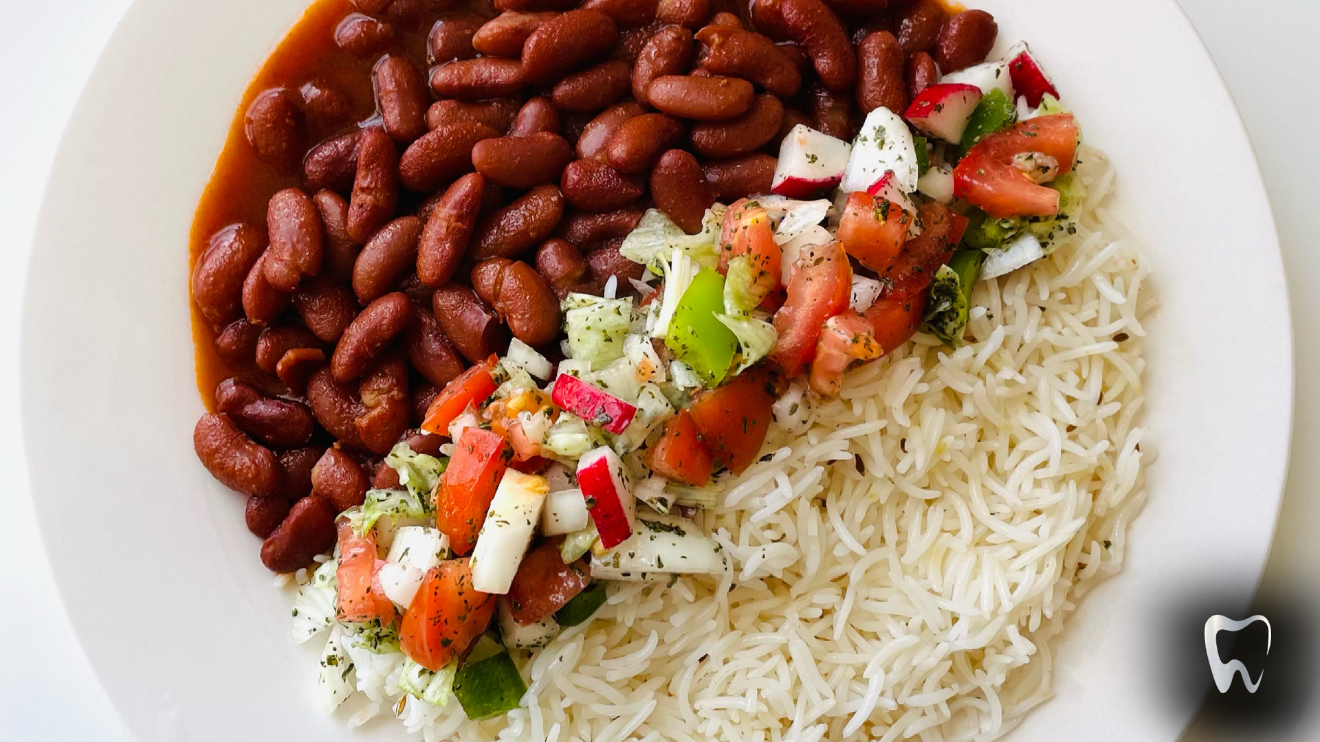A white plate topped with rice beans and vegetables