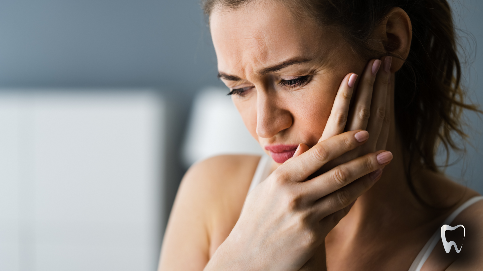 A woman is holding her face in pain because of a toothache.