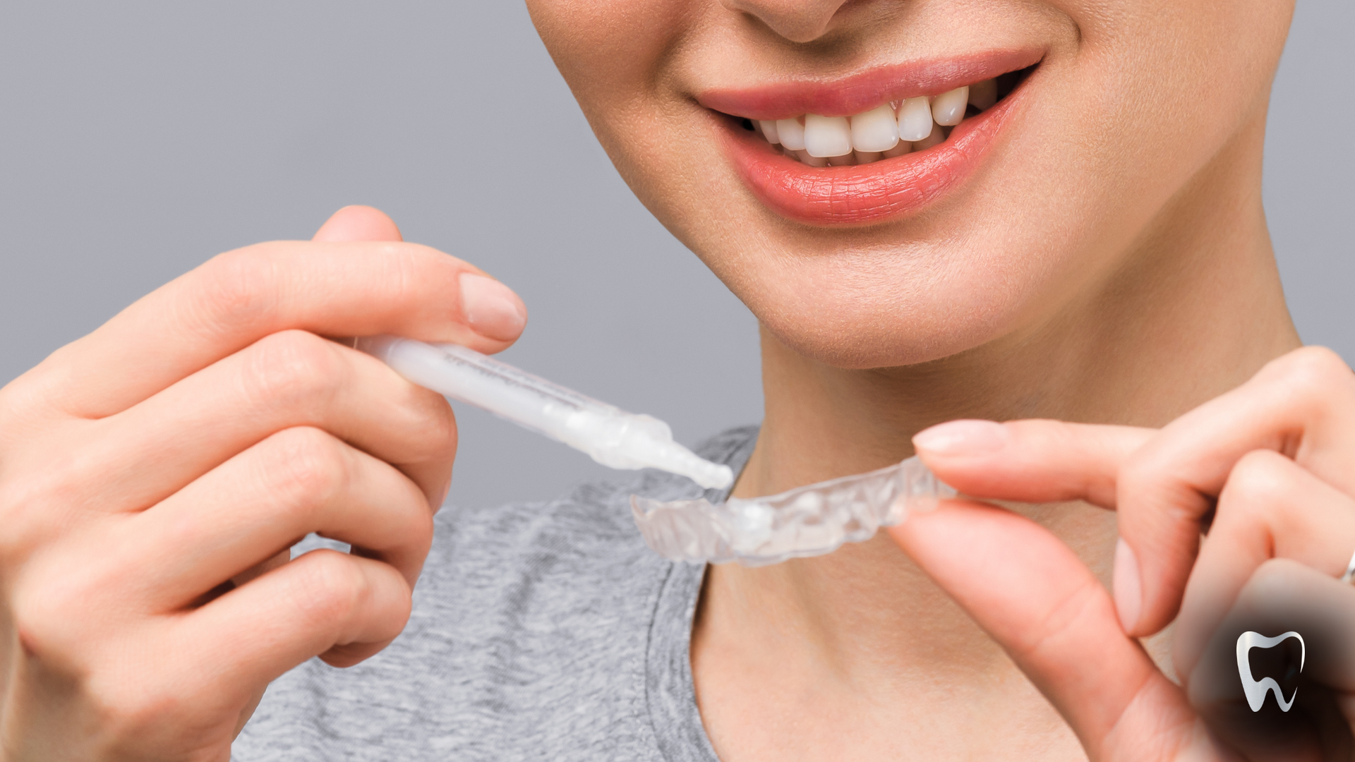 A woman is holding a tooth whitening device in her hands.