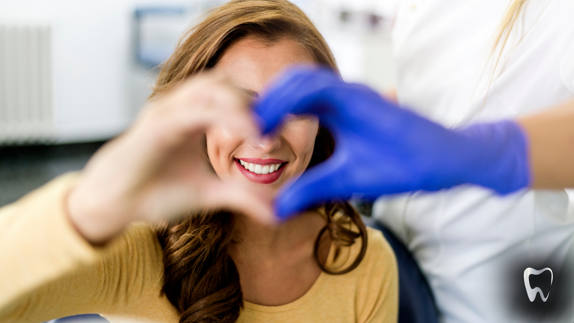 A woman is making a heart shape with her hands in a dental office.