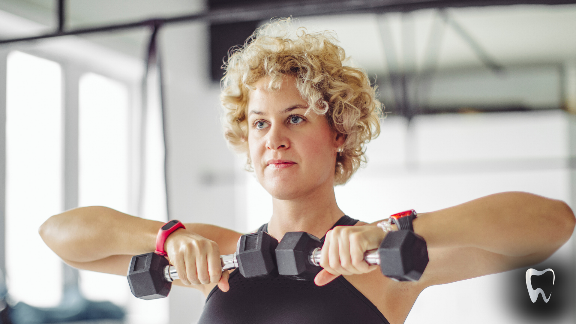 A woman is lifting dumbbells in a gym.