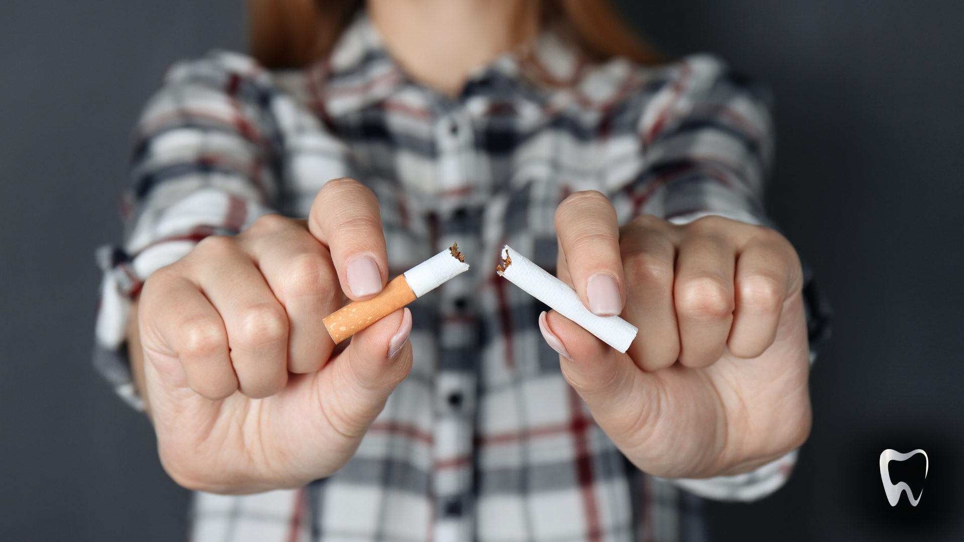 Woman breaking a cigarette in half, a sign of quitting smoking.