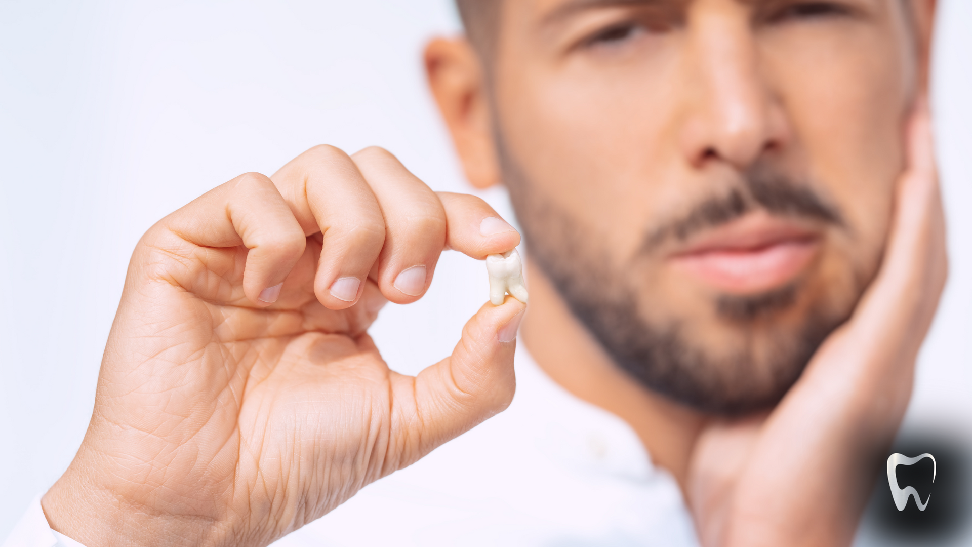 A man is holding a tooth in his hand and has a toothache.