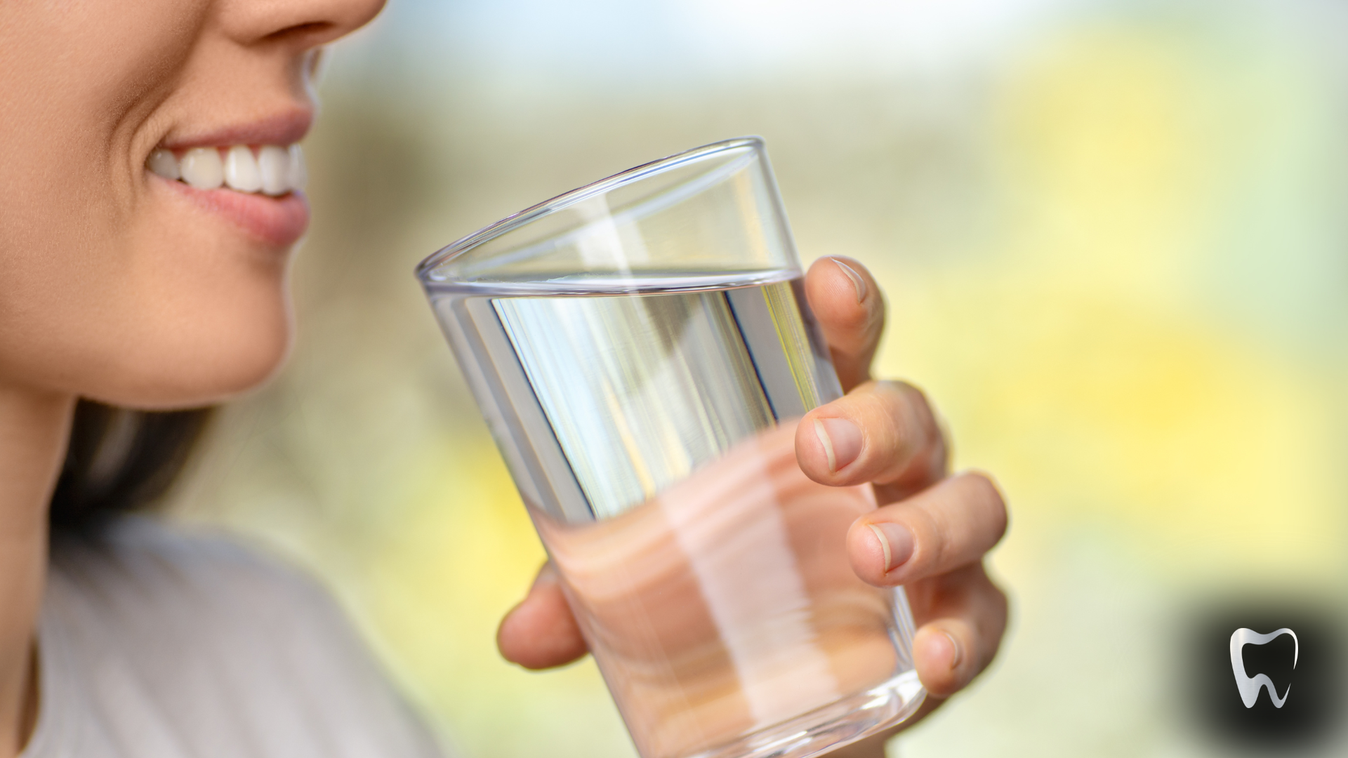 Woman smiling while drinking water from a triangular glass.