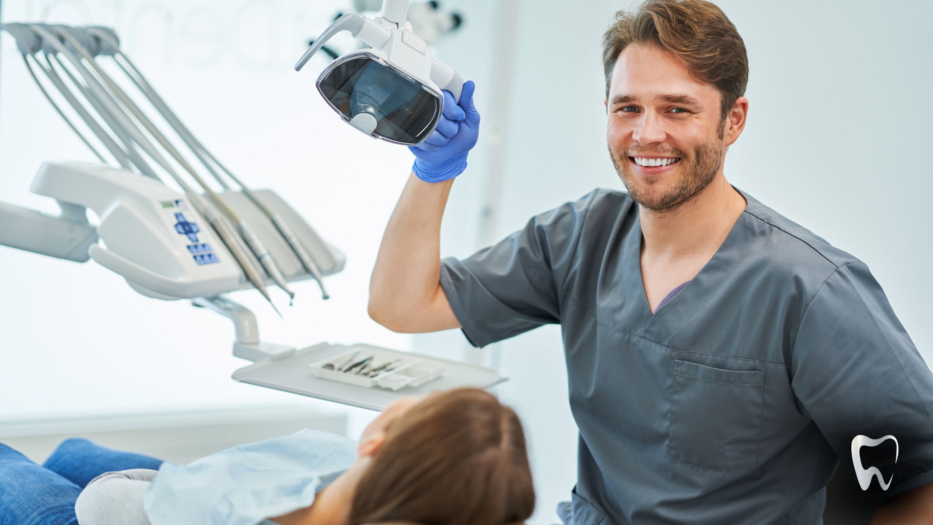 A dentist is holding a microscope in front of a patient in a dental chair.