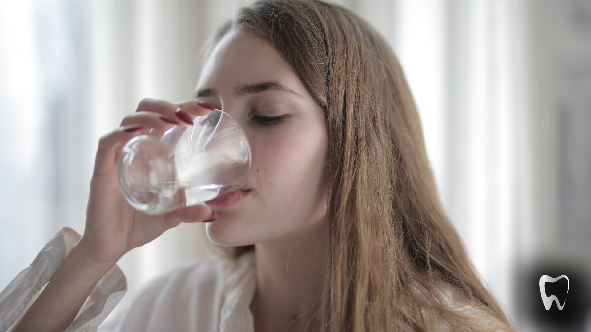 A woman is drinking a glass of water with her eyes closed.