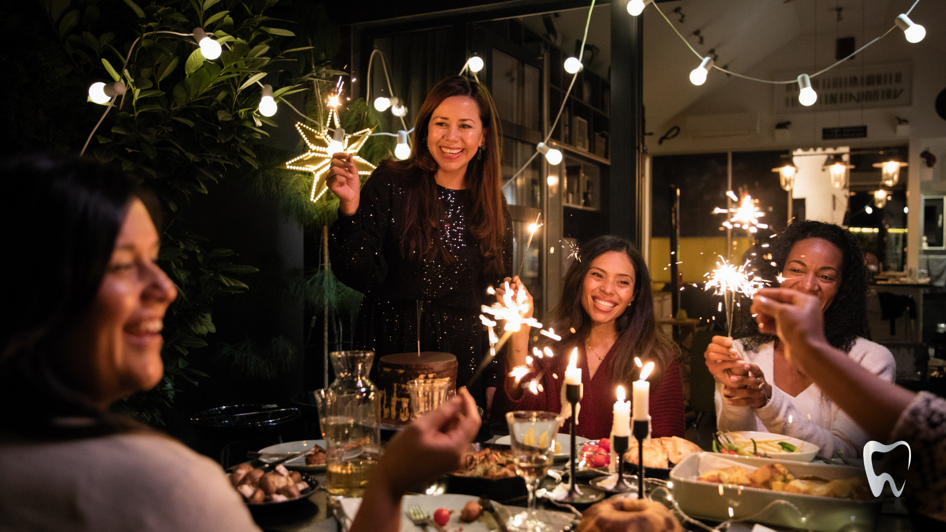 A group of women are sitting at a table holding sparklers.