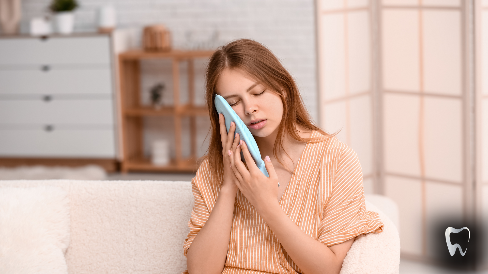 A woman is sitting on a couch holding a cell phone to her face.