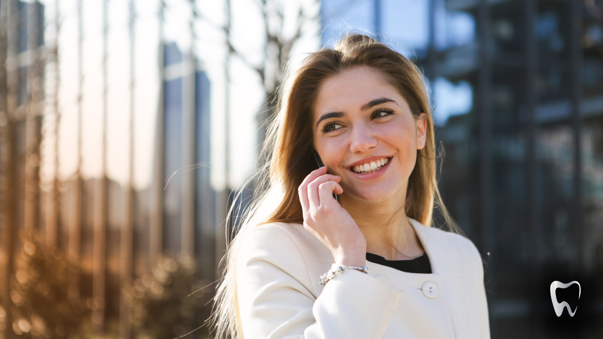 A woman is smiling while talking on a cell phone.