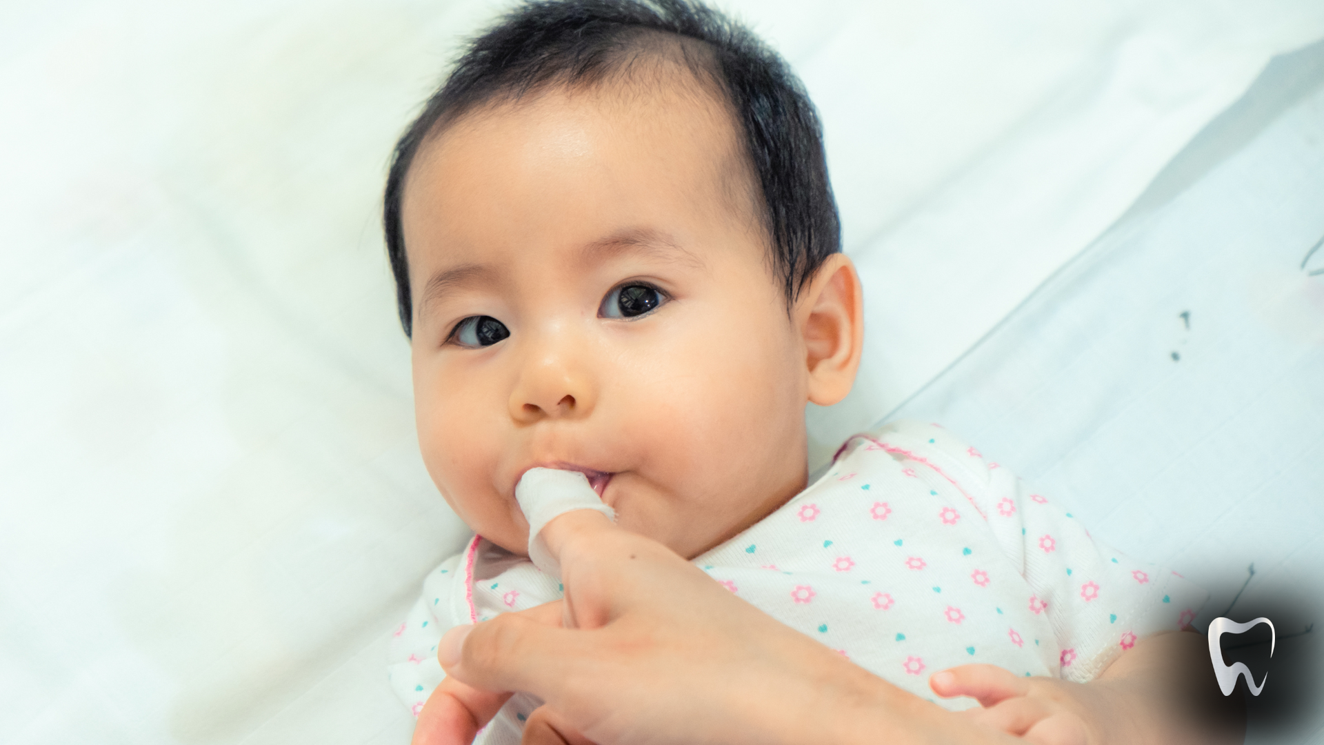 A baby is being brushed with a toothbrush by a woman.