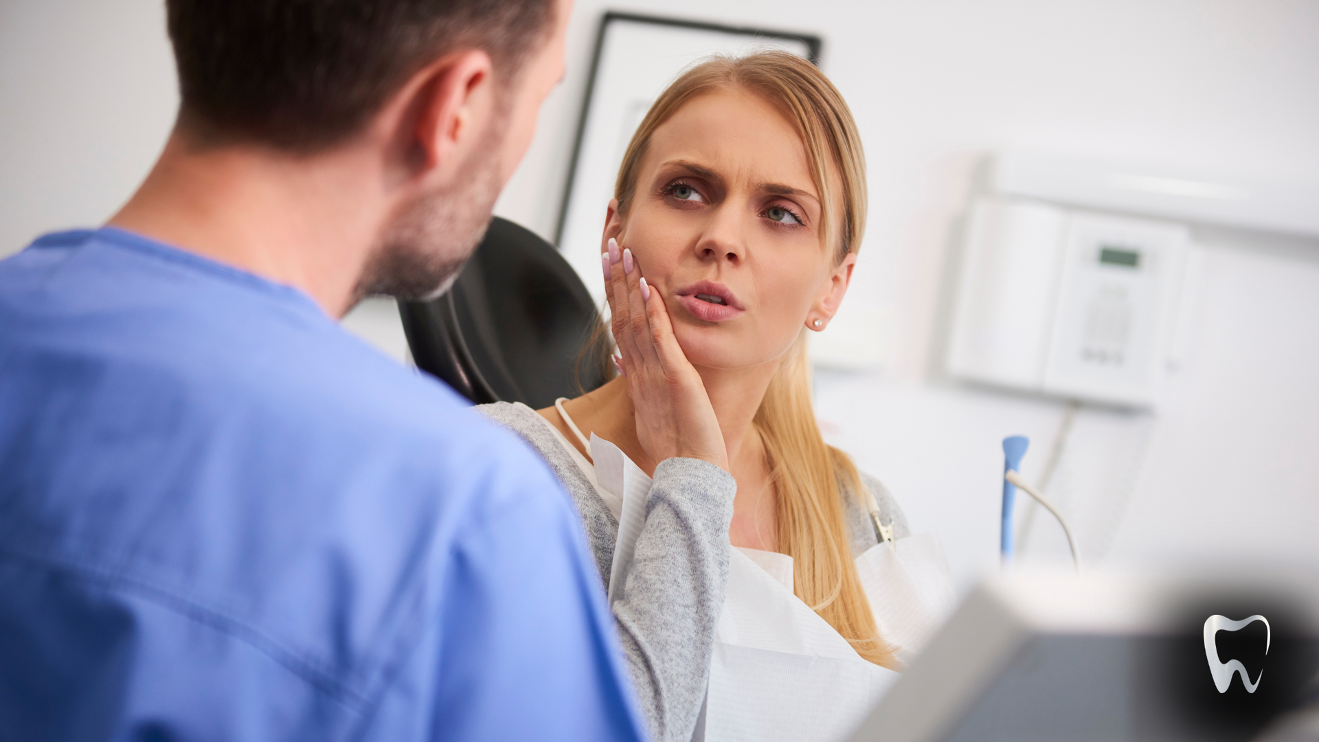 A woman is sitting in a dental chair talking to a dentist.