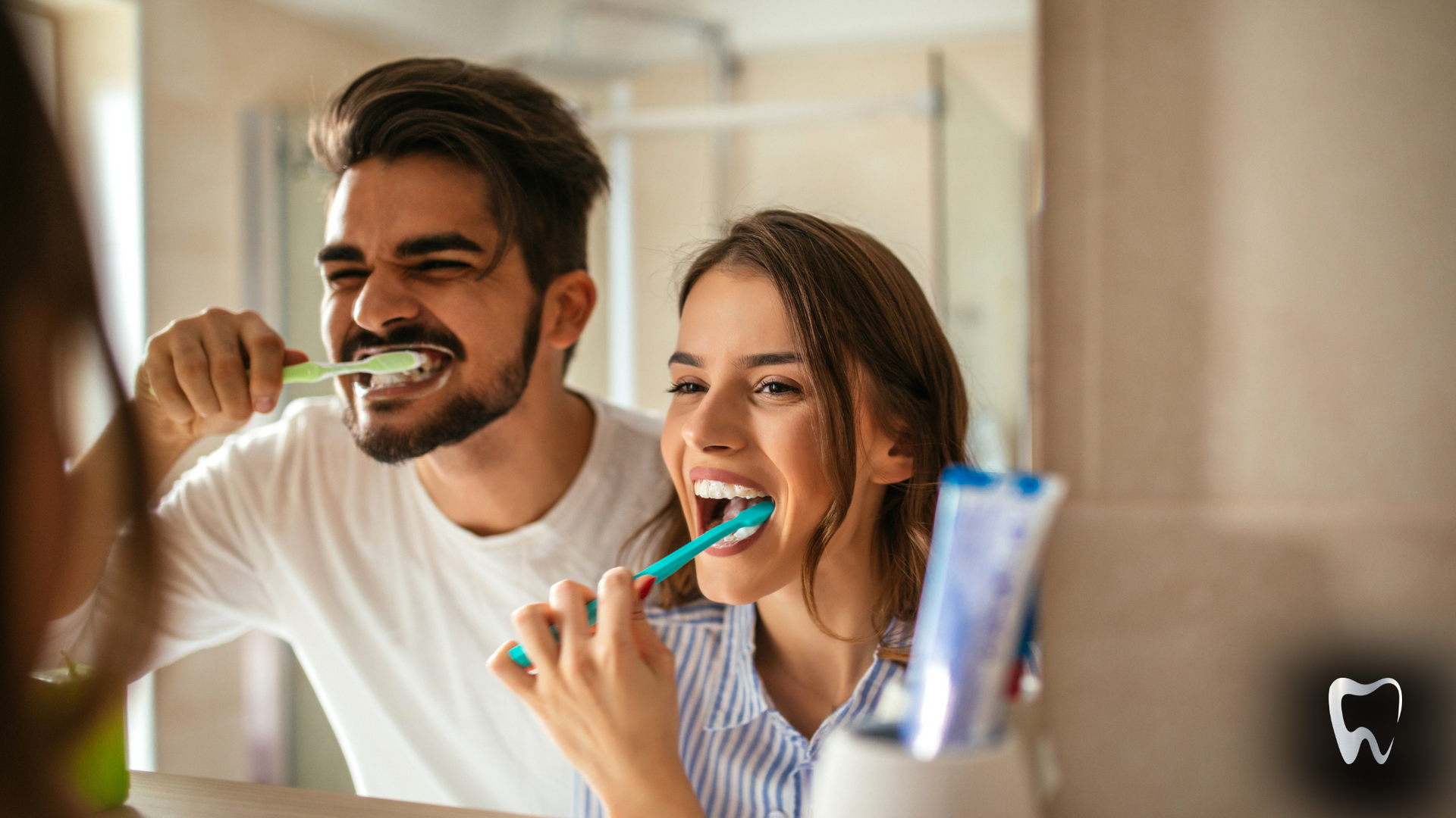 A man and a woman are brushing their teeth in front of a mirror.