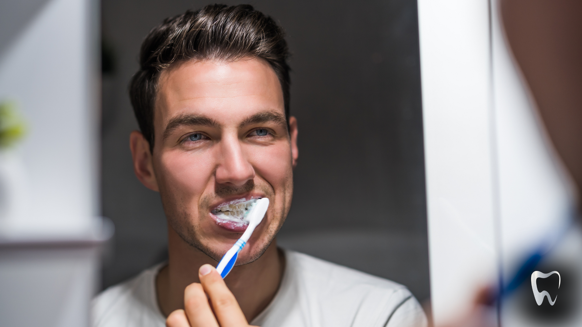 A man is brushing his teeth in front of a mirror.