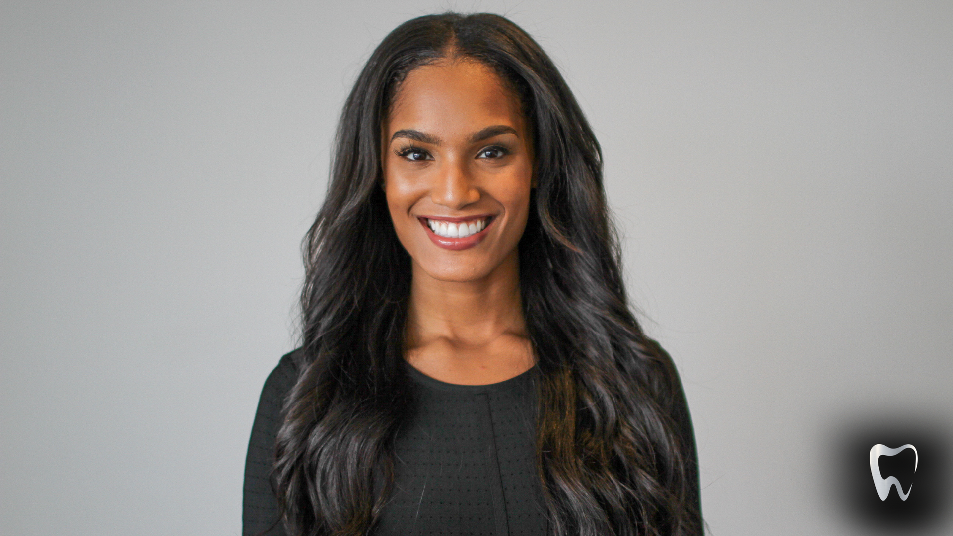 A woman with long black hair is smiling for the camera.
