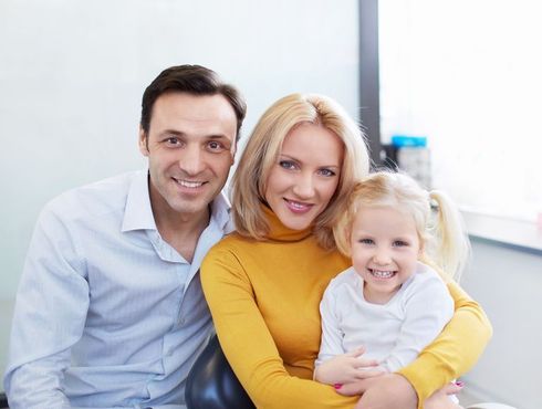 A family is posing for a picture while sitting in a dental chair.