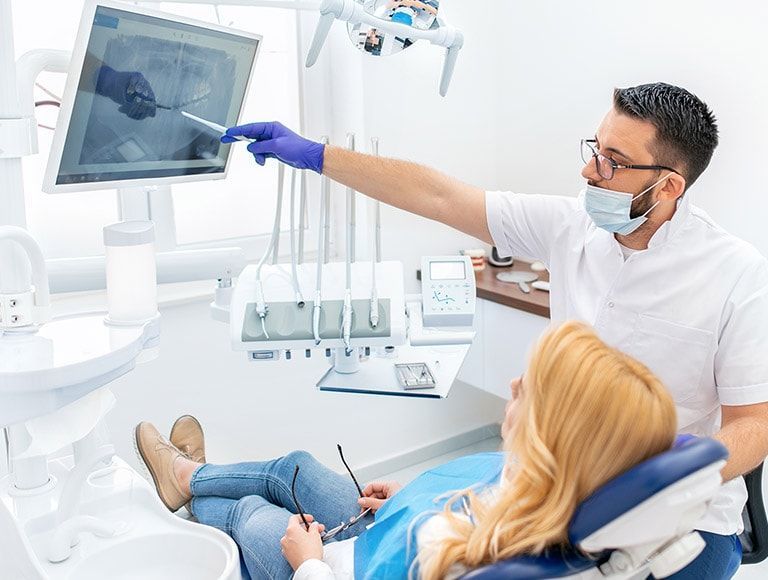 A dentist is looking at an x-ray of a patient 's teeth.