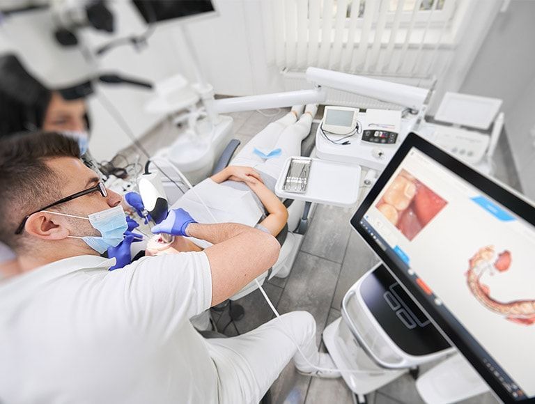 A dentist is working on a patient 's teeth in a dental office.