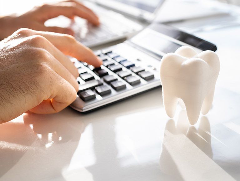 A person is typing on a calculator next to a tooth