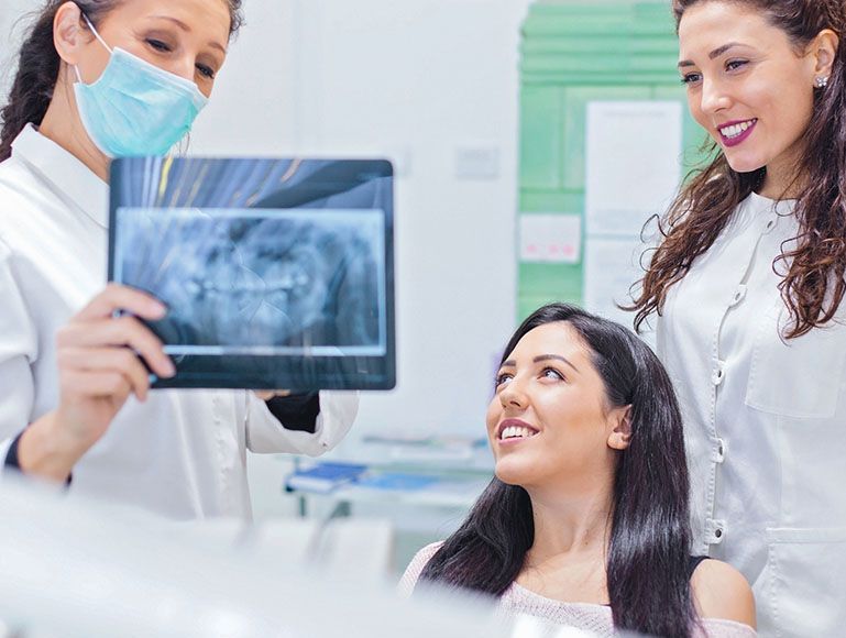 A dentist is looking at an x-ray of a woman 's teeth.