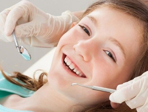 A young girl is getting her teeth examined by a dentist.