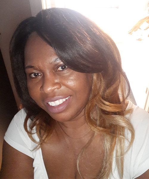 A woman with long hair is smiling and wearing a white shirt