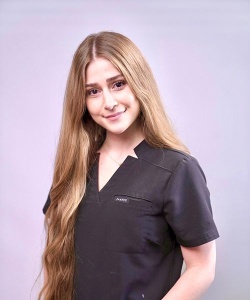 A woman with long blonde hair is wearing a black scrub top.