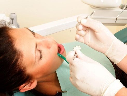 A woman is getting her teeth examined by a dentist