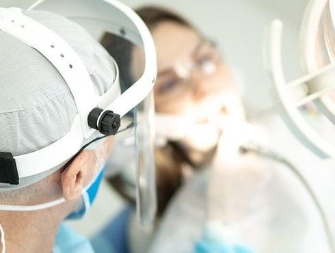 A dentist is examining a patient 's teeth in a dental office