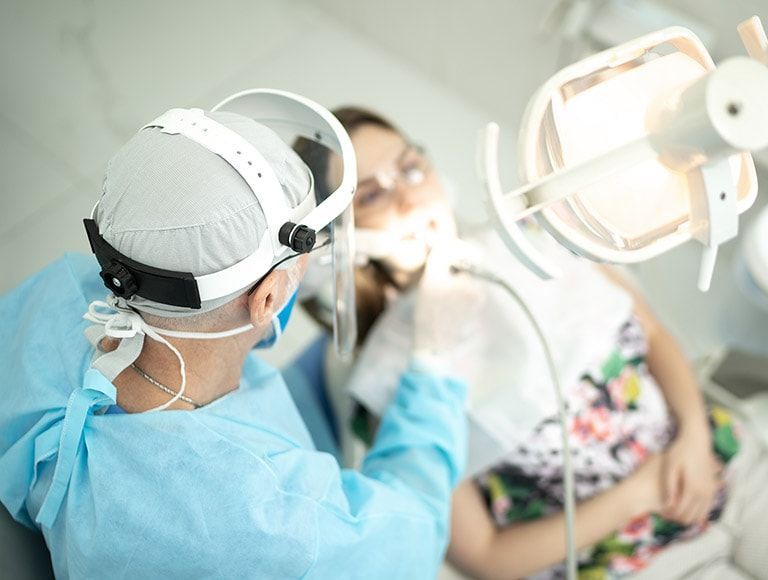 A dentist is examining a woman 's teeth in a dental office.