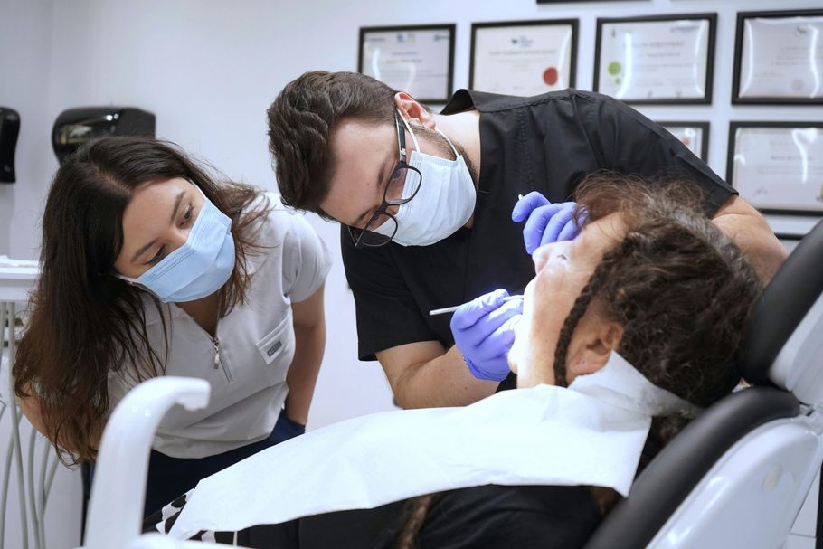 A man and a woman are examining a woman 's teeth in a dental office.