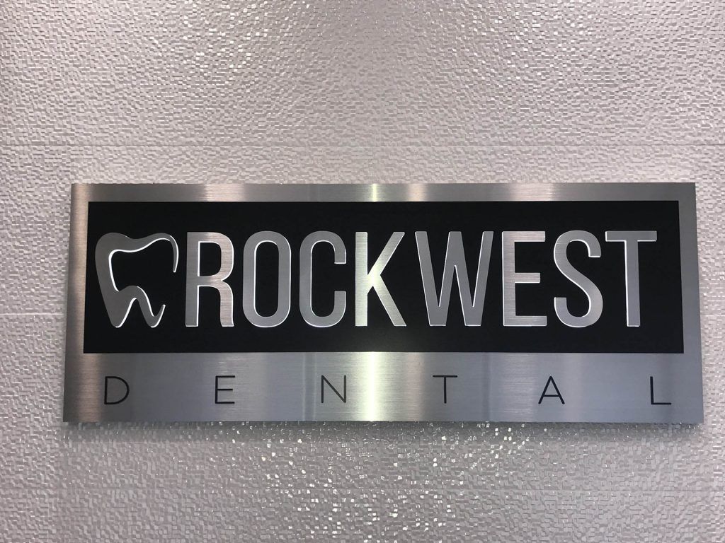A sign for rockwest dental is on a white wall.