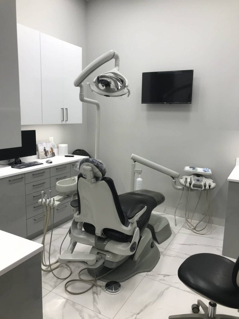 A dental office with a dental chair and a television on the wall.