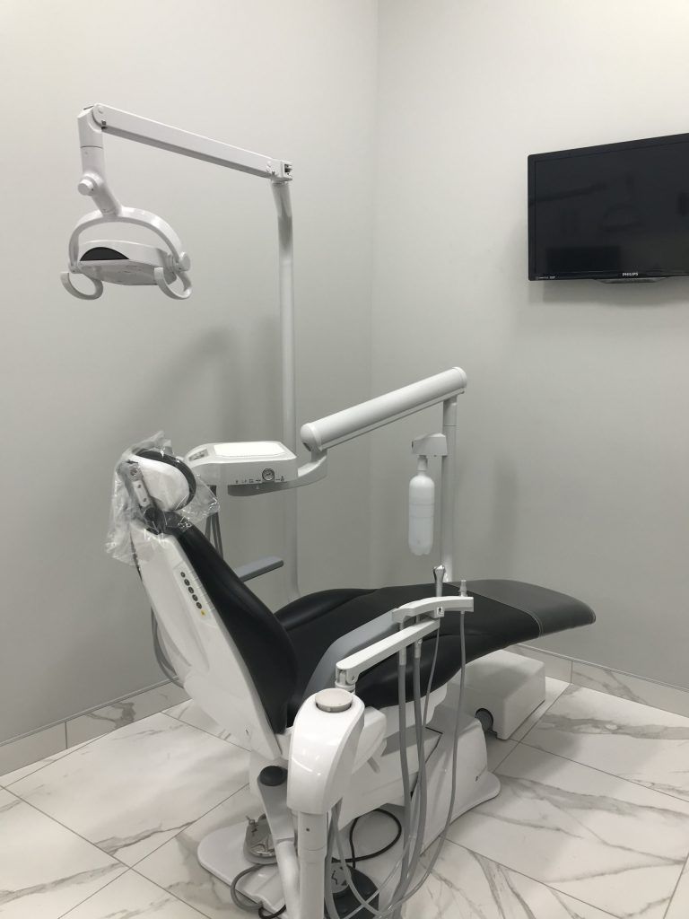 A dental chair is sitting in a dental office next to a television.