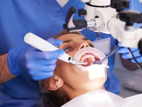 A dentist is examining a patient 's teeth under a microscope.