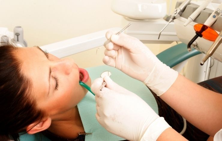 A woman is getting her teeth examined by a dentist