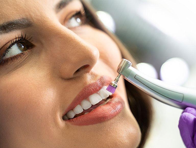 A woman is getting her teeth polished by a dentist.