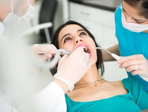 A woman is getting her teeth examined by a dentist.