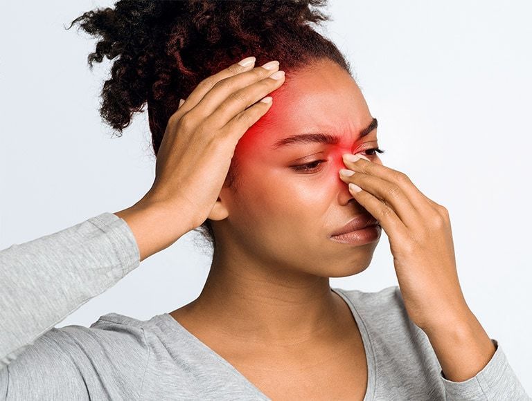 A woman is holding her nose because she has a headache.