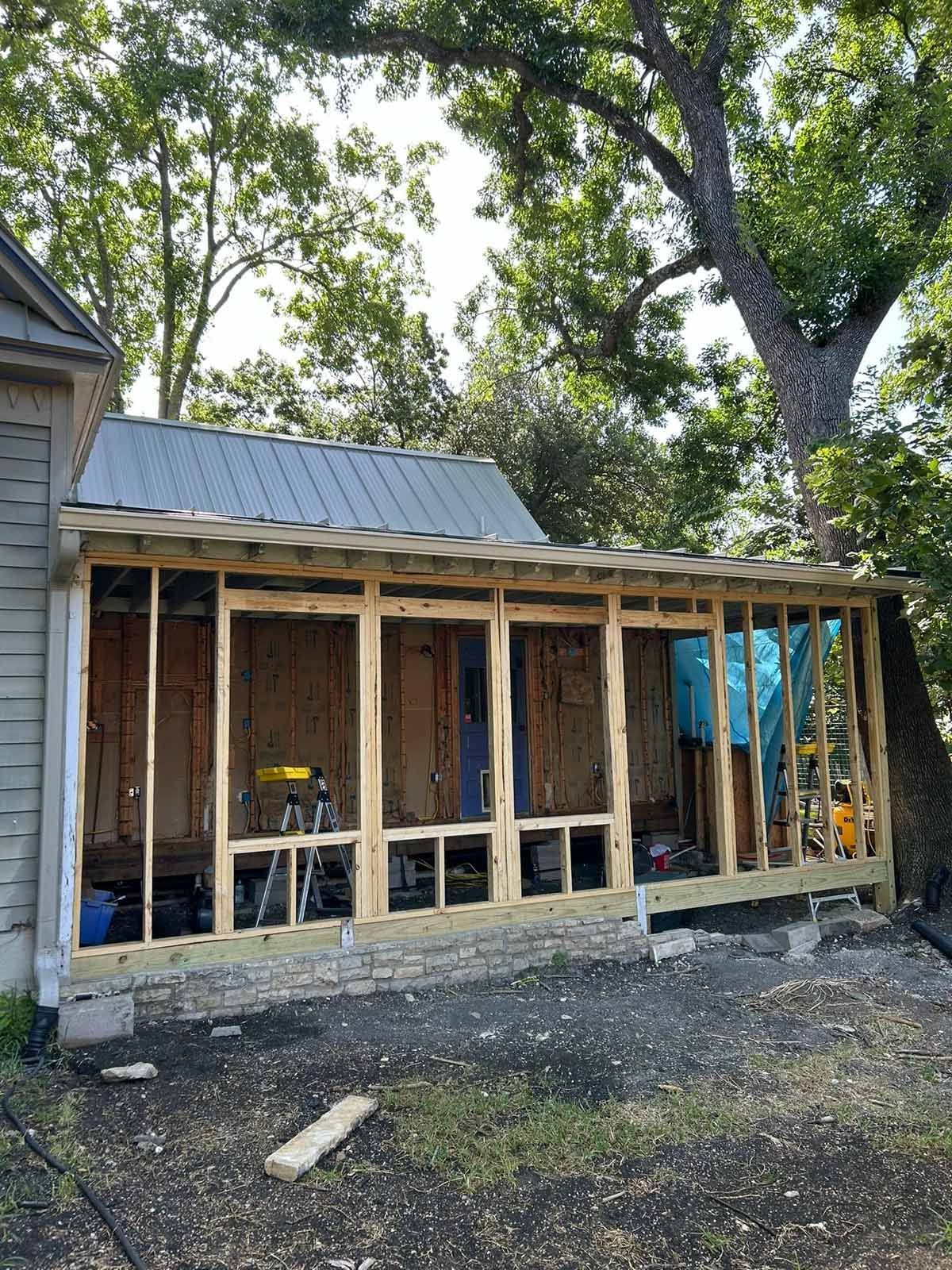 Wooden porch under construction attached to a building, tools visible.