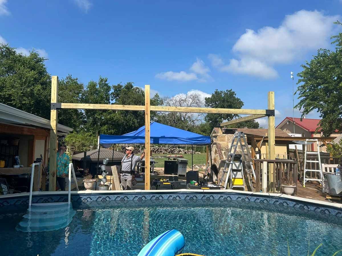 Pool with wooden structure being built, blue sky, people working.